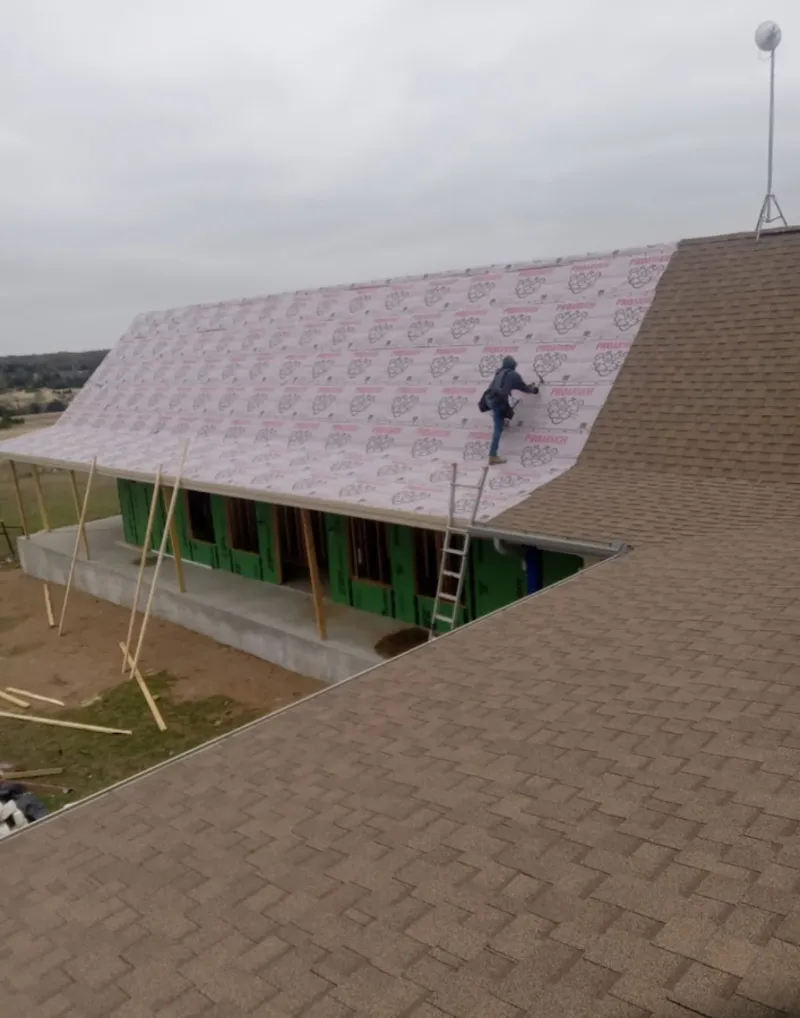 Worker preparing underlayment for a metal roof installation in Bakersfield